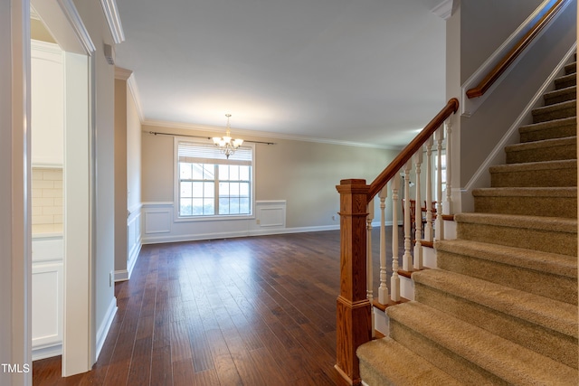 interior space featuring a wainscoted wall, a notable chandelier, ornamental molding, hardwood / wood-style flooring, and a decorative wall