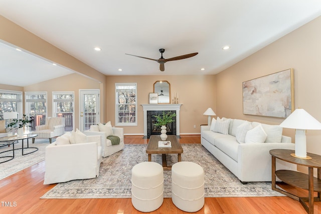 living room featuring a healthy amount of sunlight, wood finished floors, and a high end fireplace