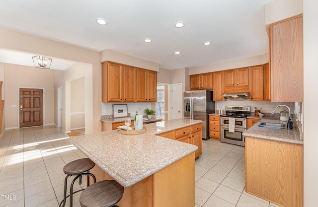 kitchen with a center island, appliances with stainless steel finishes, light tile patterned flooring, a sink, and under cabinet range hood