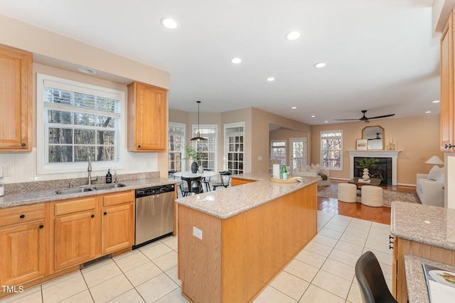 kitchen with a center island, a fireplace, light tile patterned floors, stainless steel dishwasher, and a sink