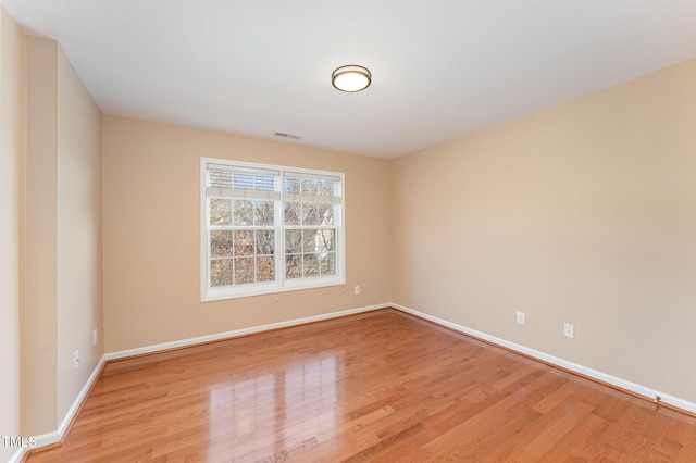 spare room featuring light wood-style flooring, visible vents, and baseboards