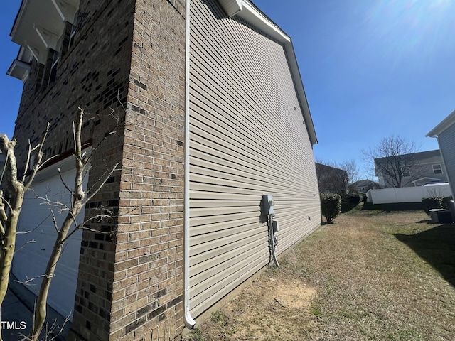 view of side of home with brick siding and fence