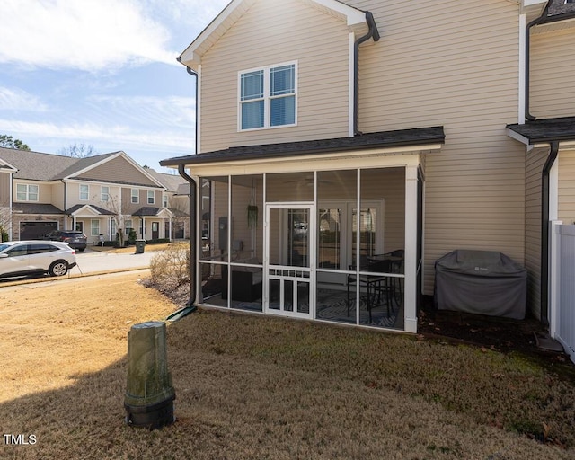 rear view of house featuring a yard and a sunroom