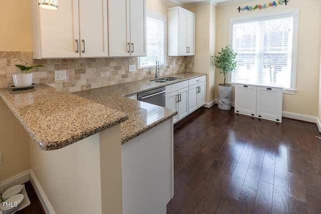 kitchen with light stone counters, a sink, decorative backsplash, dark wood-type flooring, and white cabinetry