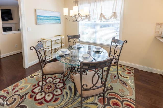 dining room featuring a notable chandelier, wood finished floors, and baseboards