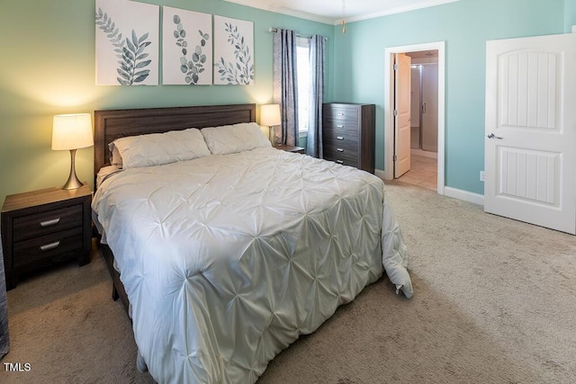 bedroom featuring crown molding, carpet flooring, baseboards, and ensuite bathroom