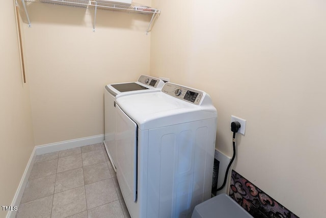 laundry room with washer and clothes dryer, laundry area, baseboards, and light tile patterned floors