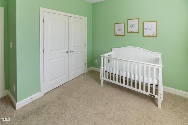 carpeted bedroom with a nursery area, baseboards, and a closet