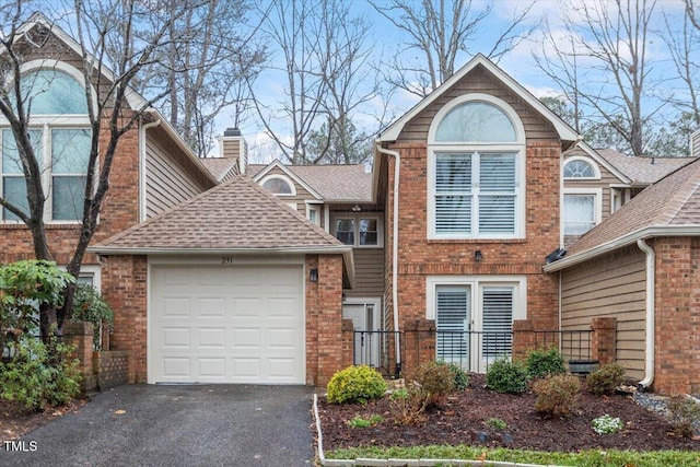 view of front of property with a garage, brick siding, driveway, and roof with shingles