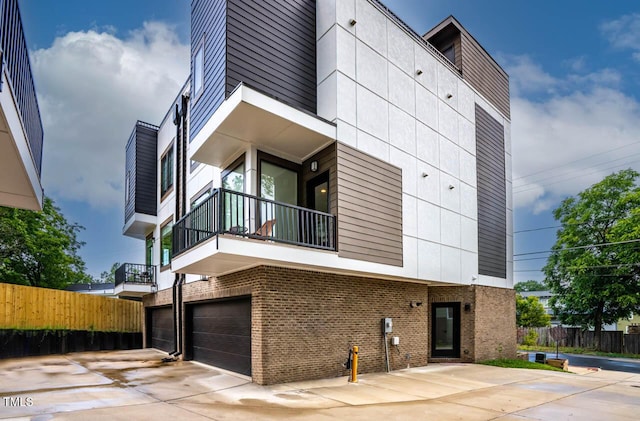 exterior space with a garage, brick siding, and fence