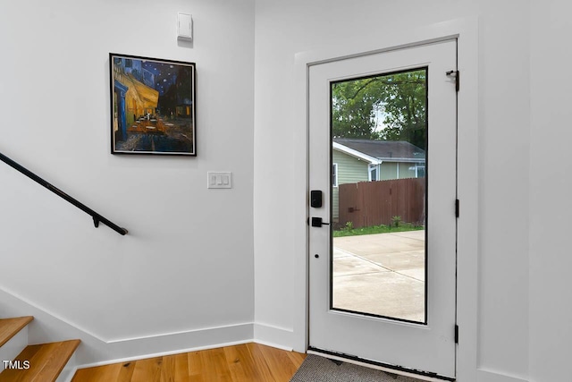 doorway with stairs, wood finished floors, and baseboards