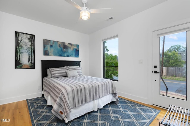 bedroom featuring access to exterior, wood finished floors, visible vents, and baseboards