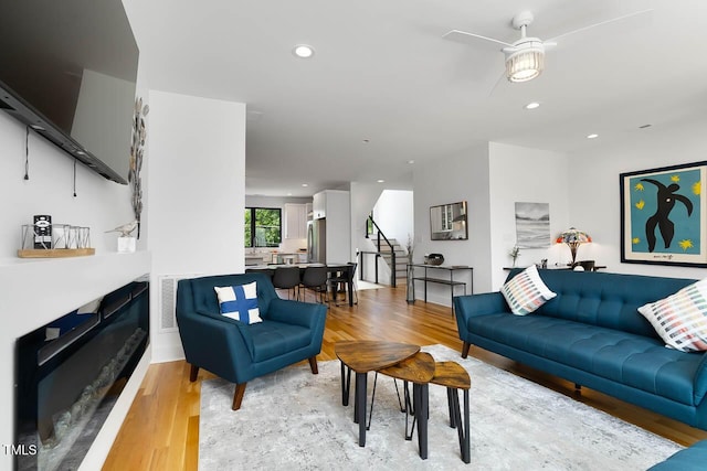 living area with light wood finished floors, recessed lighting, visible vents, stairway, and a glass covered fireplace