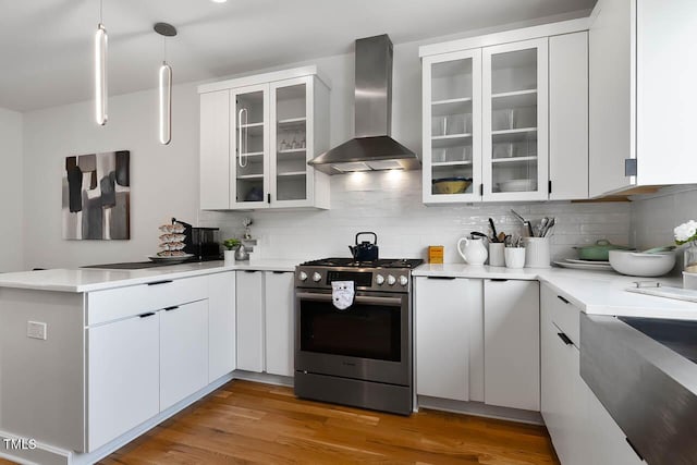 kitchen with a peninsula, wall chimney exhaust hood, decorative backsplash, and gas stove