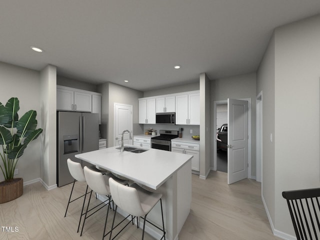 kitchen featuring a center island with sink, a sink, stainless steel appliances, light countertops, and a kitchen bar