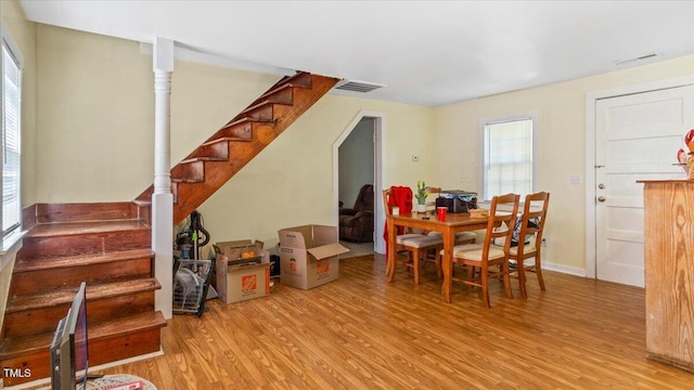 dining space with light wood-style floors, visible vents, and stairs