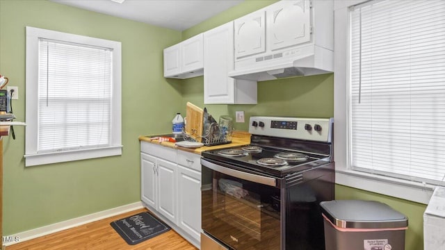 kitchen featuring light countertops, white cabinetry, stainless steel range with electric stovetop, under cabinet range hood, and baseboards