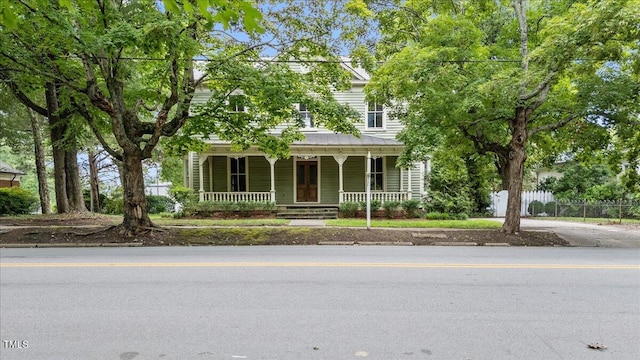 view of front facade with covered porch, fence, and metal roof