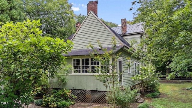 view of property exterior with metal roof and a chimney