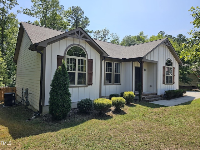 ranch-style house with cooling unit, a front lawn, board and batten siding, and roof with shingles