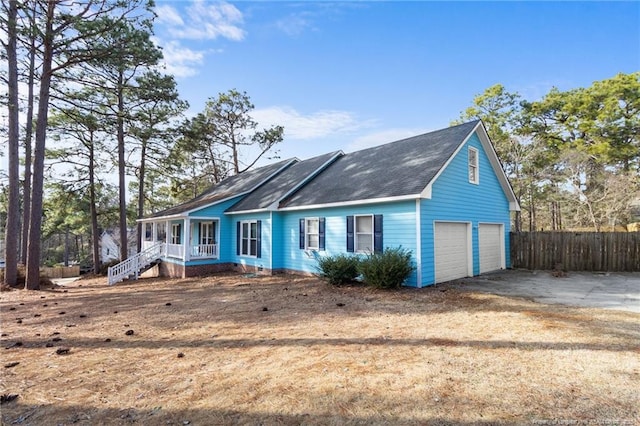 view of front of home featuring a garage, driveway, fence, and a porch