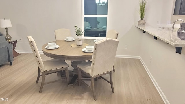 dining room with light wood-style flooring, baseboards, and a chandelier