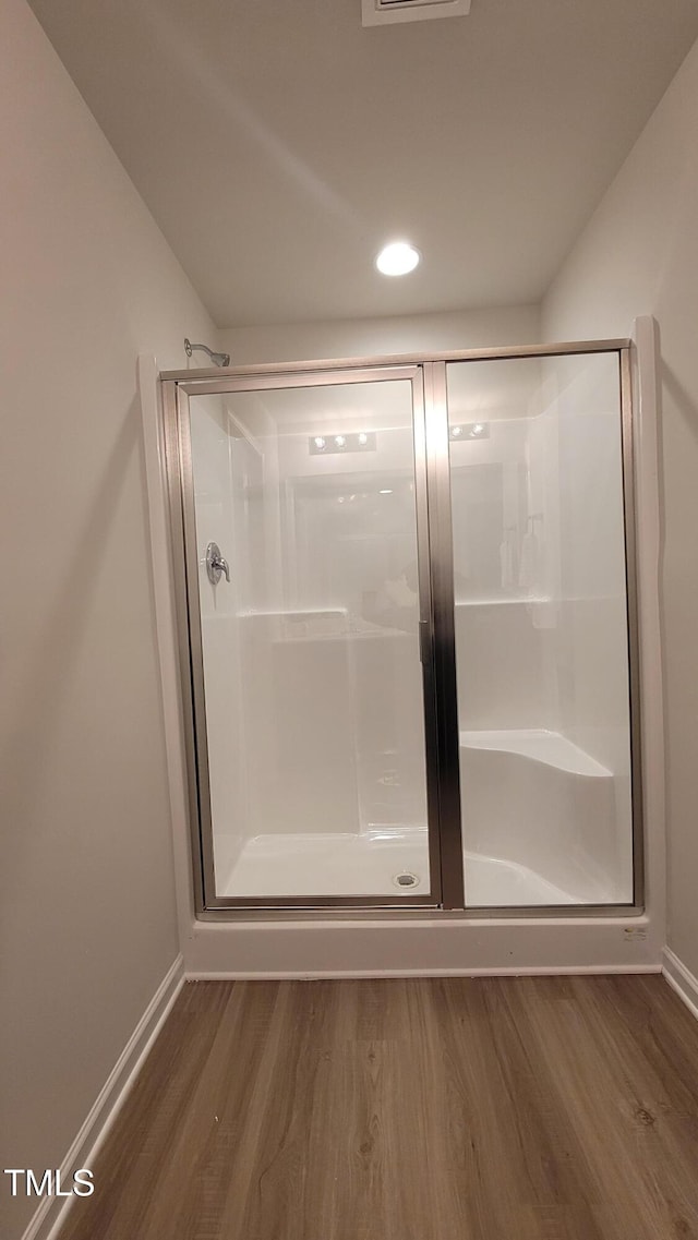 full bathroom with a shower stall, baseboards, and wood finished floors