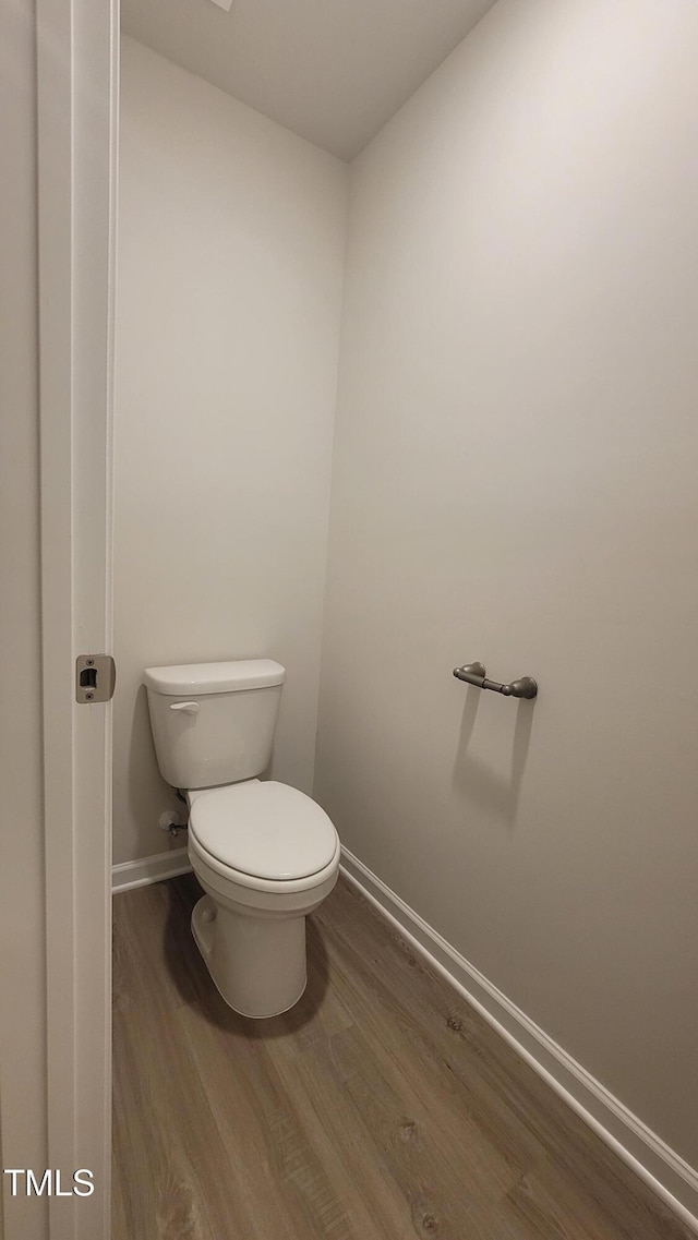 bathroom with toilet, baseboards, and wood finished floors