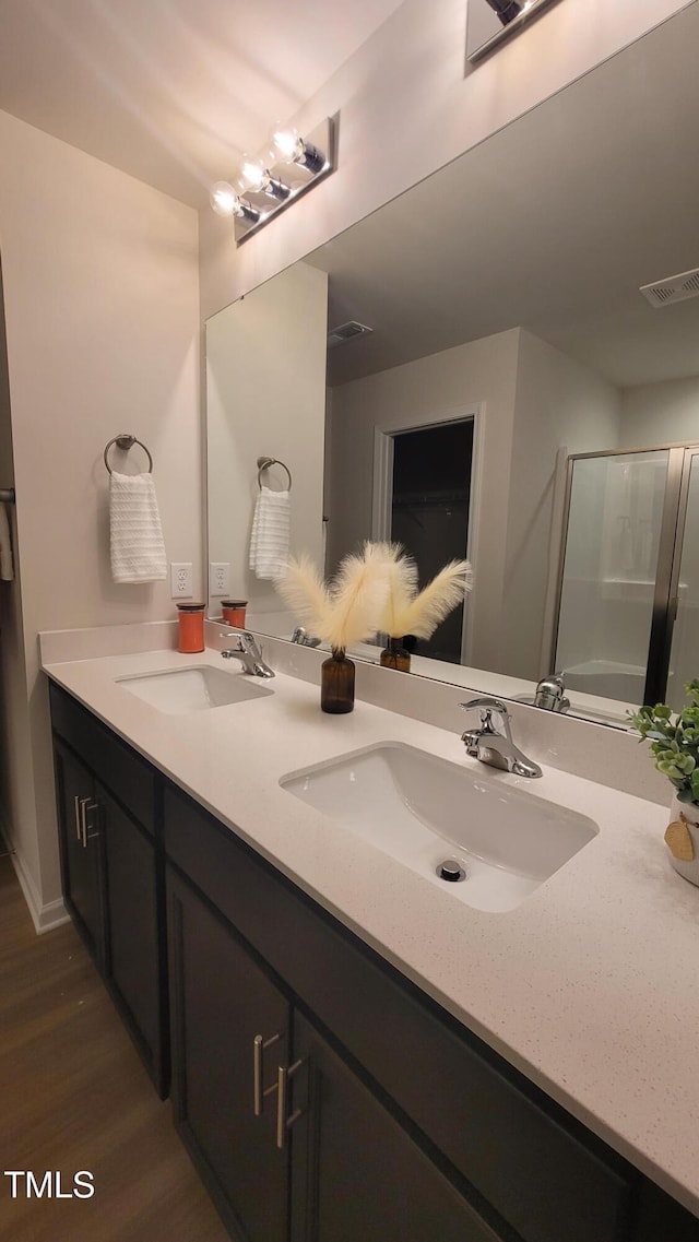 bathroom with double vanity, visible vents, a sink, and an enclosed shower