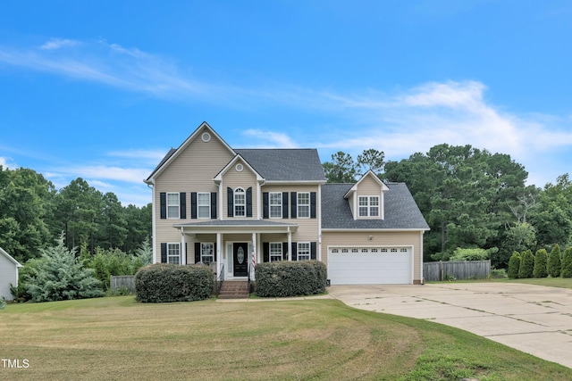 colonial home with a front yard, driveway, an attached garage, and fence