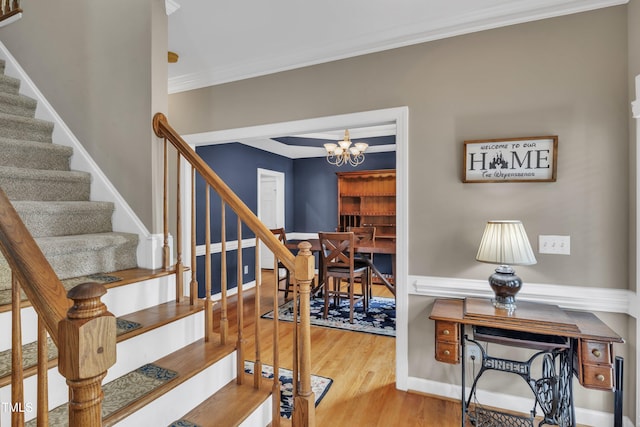 stairs featuring baseboards, a chandelier, wood finished floors, and ornamental molding