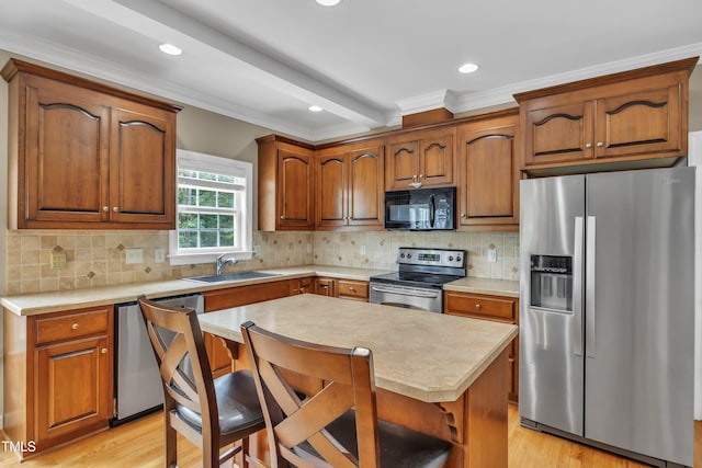 kitchen featuring a sink, light countertops, appliances with stainless steel finishes, and a kitchen bar