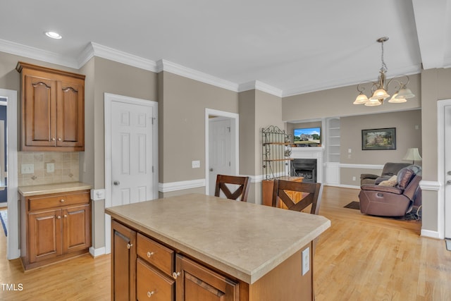 kitchen with a kitchen island, open floor plan, light countertops, light wood-style floors, and a fireplace