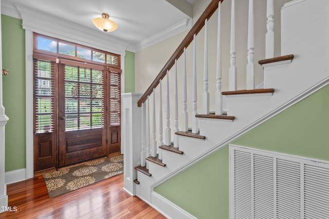 foyer entrance featuring wood finished floors, visible vents, baseboards, stairs, and ornamental molding