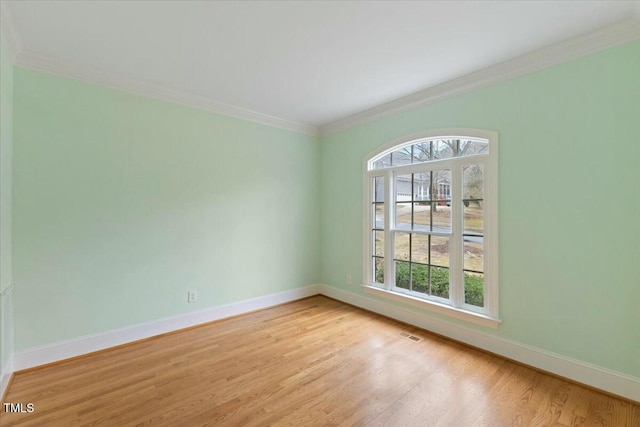 empty room with visible vents, crown molding, light wood-style flooring, and baseboards