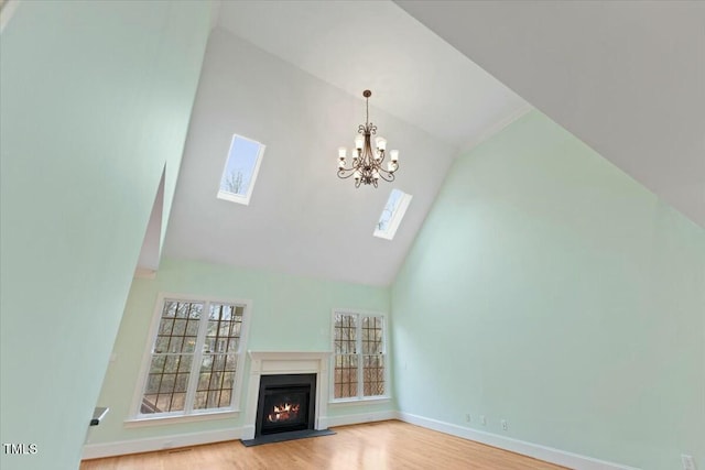 unfurnished living room with light wood-style flooring, high vaulted ceiling, baseboards, and a lit fireplace