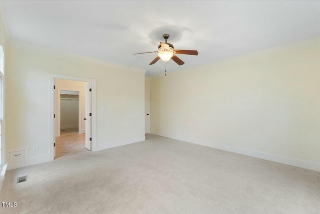 empty room with baseboards, visible vents, crown molding, and light colored carpet