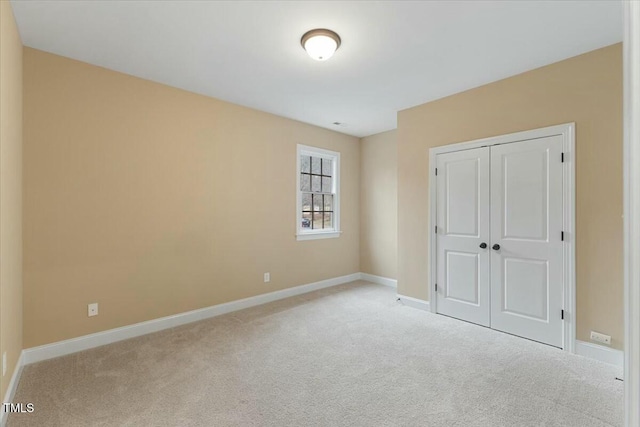 unfurnished bedroom featuring baseboards, a closet, and light colored carpet