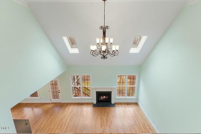 unfurnished living room with a healthy amount of sunlight, light wood-style floors, a fireplace with flush hearth, and lofted ceiling with skylight