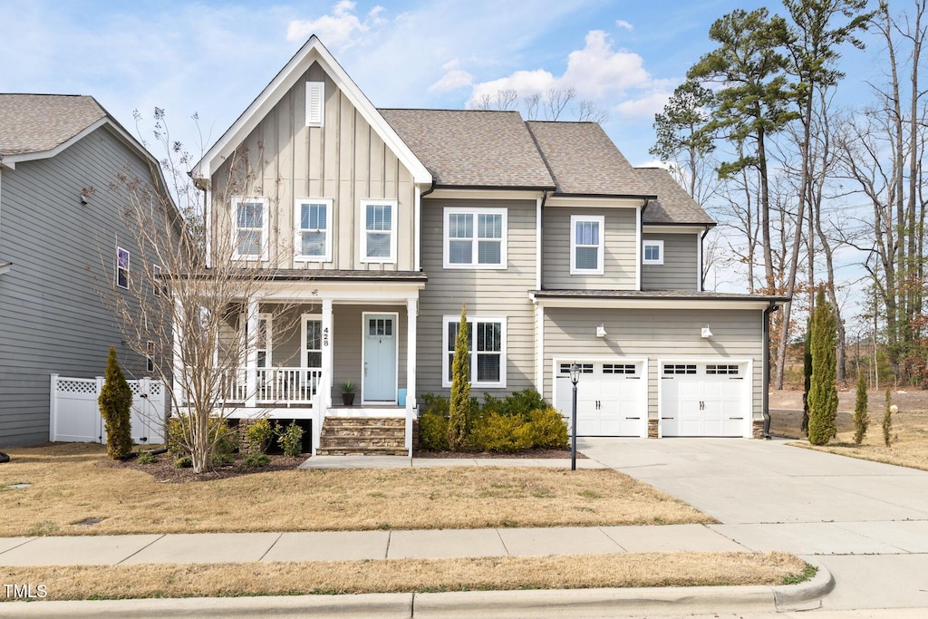 craftsman-style home featuring covered porch, a garage, driveway, roof with shingles, and board and batten siding