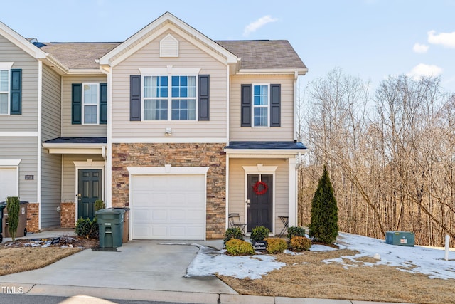 view of property with stone siding, driveway, and an attached garage