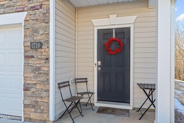 doorway to property featuring a garage and stone siding