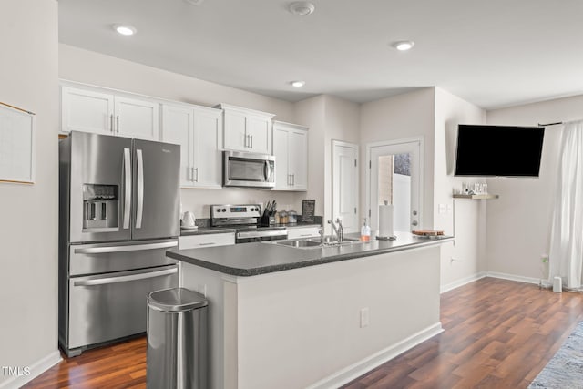 kitchen with appliances with stainless steel finishes, dark countertops, a sink, and white cabinets