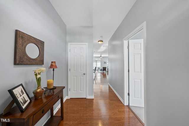 corridor featuring baseboards and wood finished floors