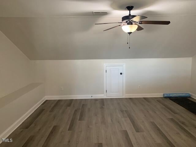 additional living space with visible vents, vaulted ceiling, baseboards, and wood finished floors