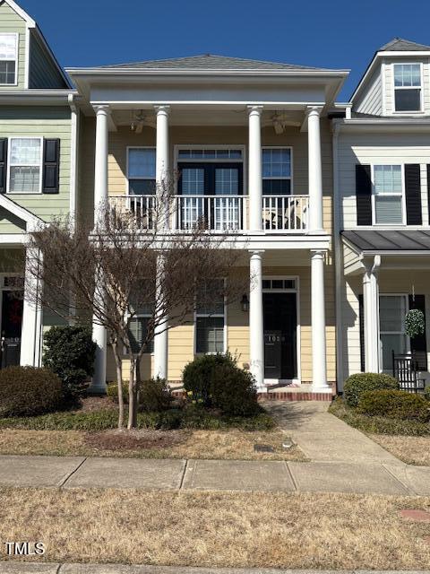 neoclassical home featuring a porch and a balcony