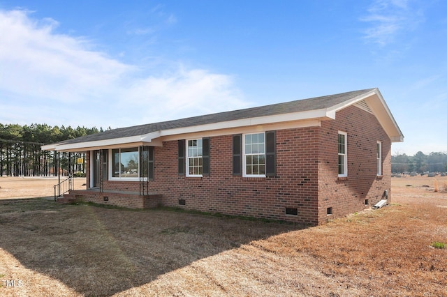 view of front of house with a front lawn, brick siding, and crawl space