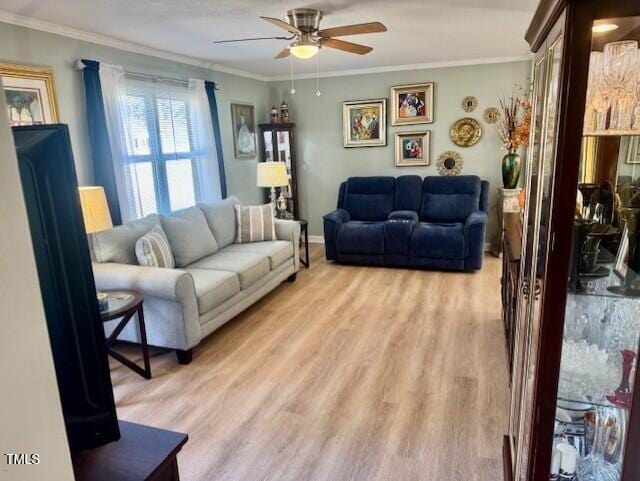 living area featuring light wood-style floors, ceiling fan, ornamental molding, and baseboards