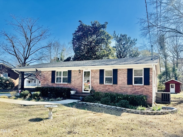 single story home with a front yard, an outbuilding, central AC, and brick siding