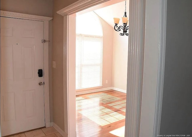 doorway featuring light tile patterned floors, baseboards, and a notable chandelier